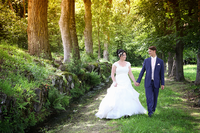Photo de jeunes mariés se tenant la main et marchant dans la forêt