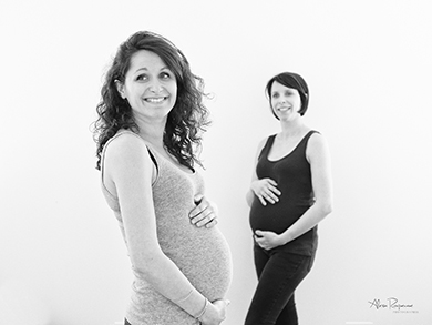 Photo de deux femmes enceintes heureuses se tenant le ventre.